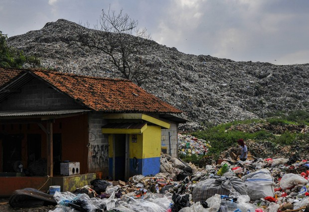 Warga berjalan dengan latar belakang tumpukan sampah di TPA (Tempat Pembuangan Akhir) Burangkeng, Setu, Kabupaten Bekasi, Jawa Barat, Rabu (8/6/2022). (ANTARA FOTO/ Fakhri Hermansyah)