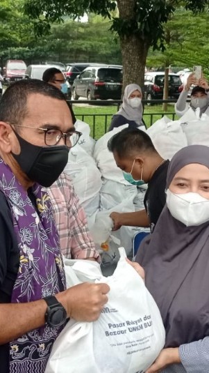 Staf Khusus Menteri BUMN Arya Sinulingga menyerahkan paket sembako murah kepada masyarakat dalam kegiatan pasar rakyat dan bazar UMKM BUMN di Pondok Cabe, Tangerang Selatan, Banten, Sabtu (18/6/2022).